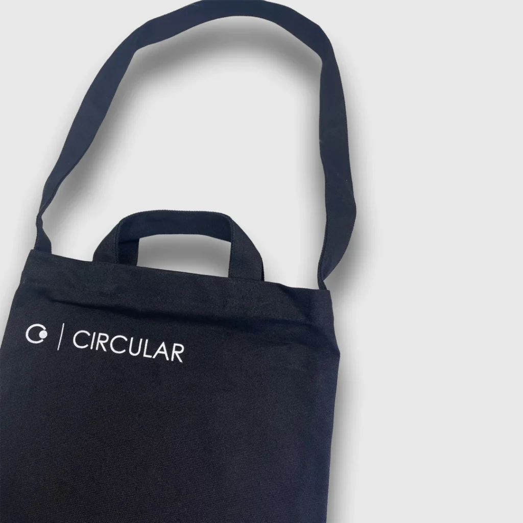 Navy blue material carrier bag with white circular logo