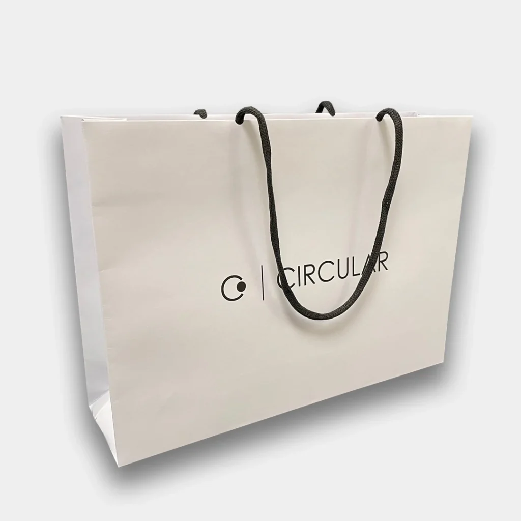 White carrier bag with black handle and circular log on the front