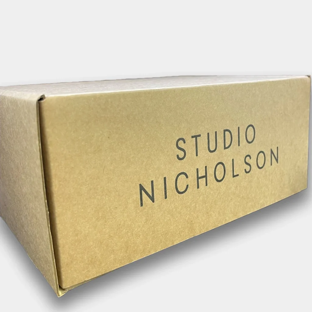 Brown e-commerce box with large Studio Nicholson logo on the side